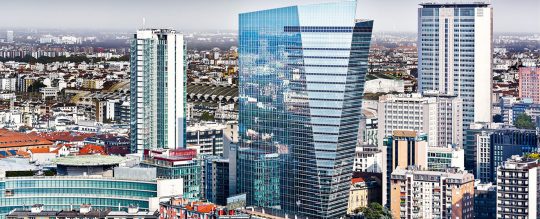 The image depicts the skyline of Milan, highlighting the "La Scheggia" skyscraper, home to Fideuram Intesa Sanpaolo Private Banking (FISPB)