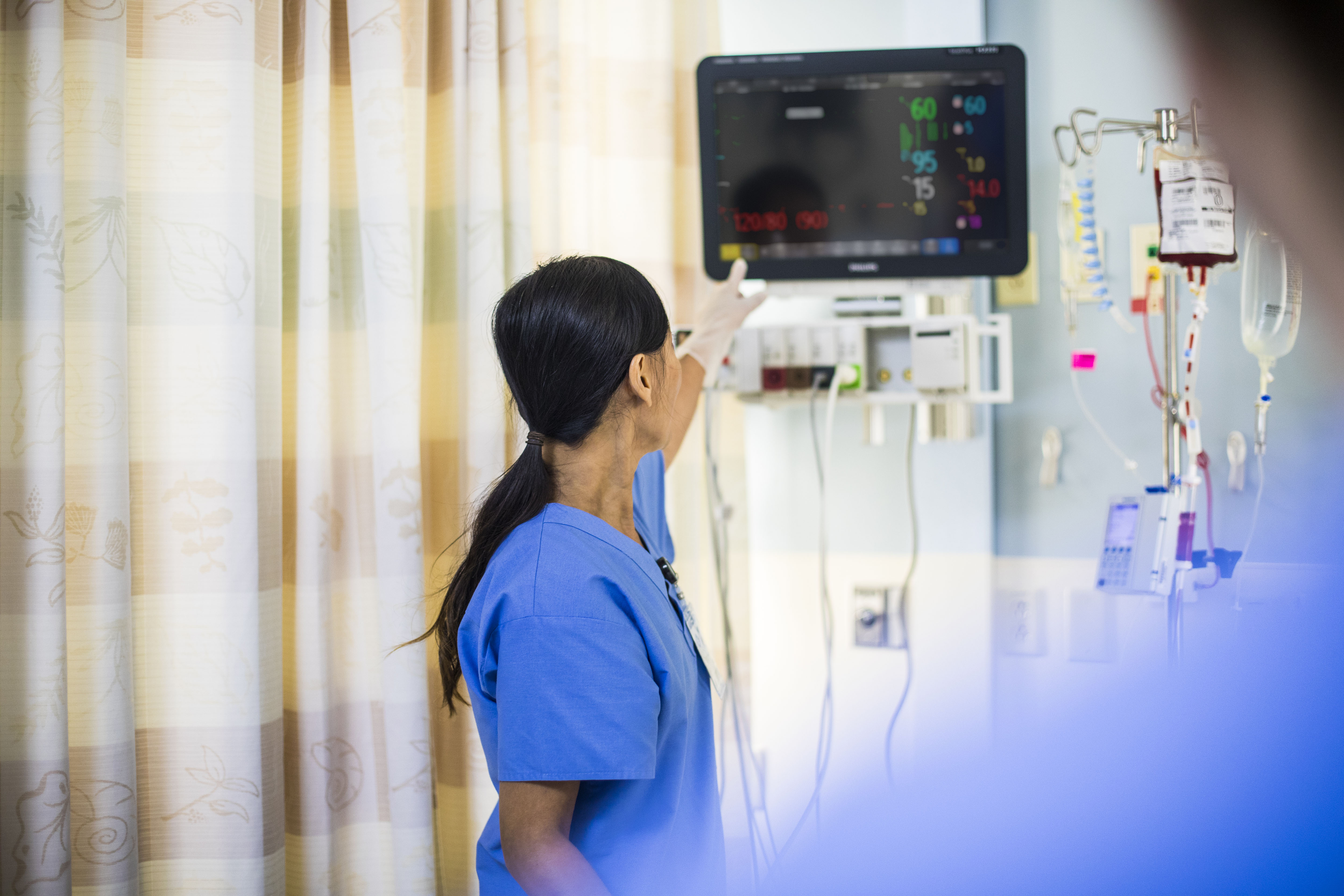 An acute care nurse turns off a bedside alarm