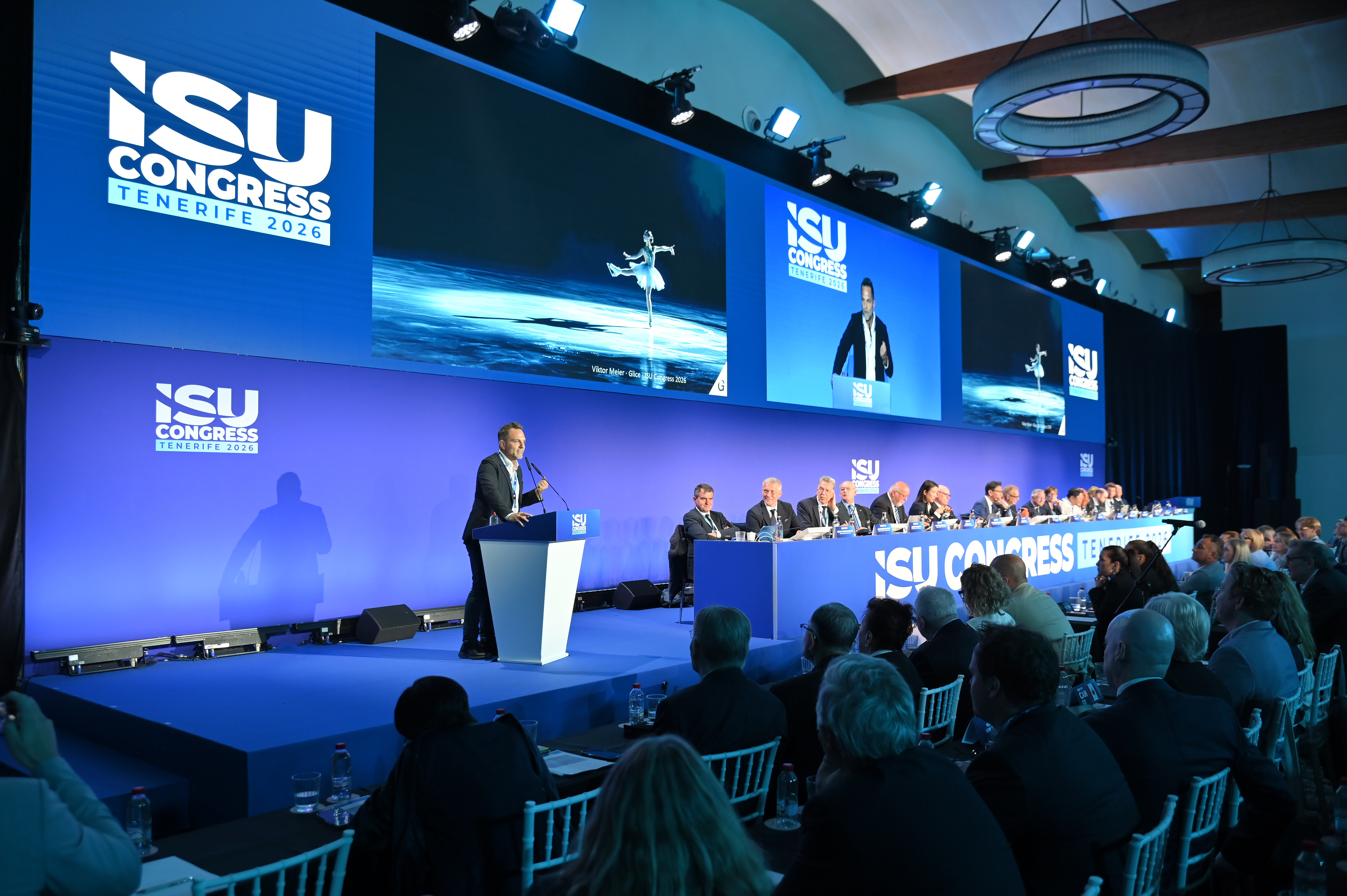 A medium wide shot of Glice Co-Founder and CEO Viktor Meier standing at a blue and white branded ISU podium.